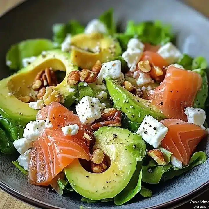 Avocado and smoked salmon salad with feta cheese and walnuts served in a bowl.