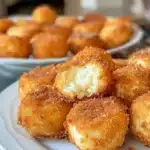 Delicious crispy fried cheesecake bites served on a plate with a drizzle of chocolate.