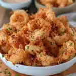 Crispy mini blooming onions cooked in an air fryer, served as a tasty appetizer.